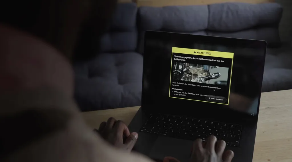 Person schaut auf einem Tablet eine Videoanleitung mit eingeblendetem Warnhinweis
