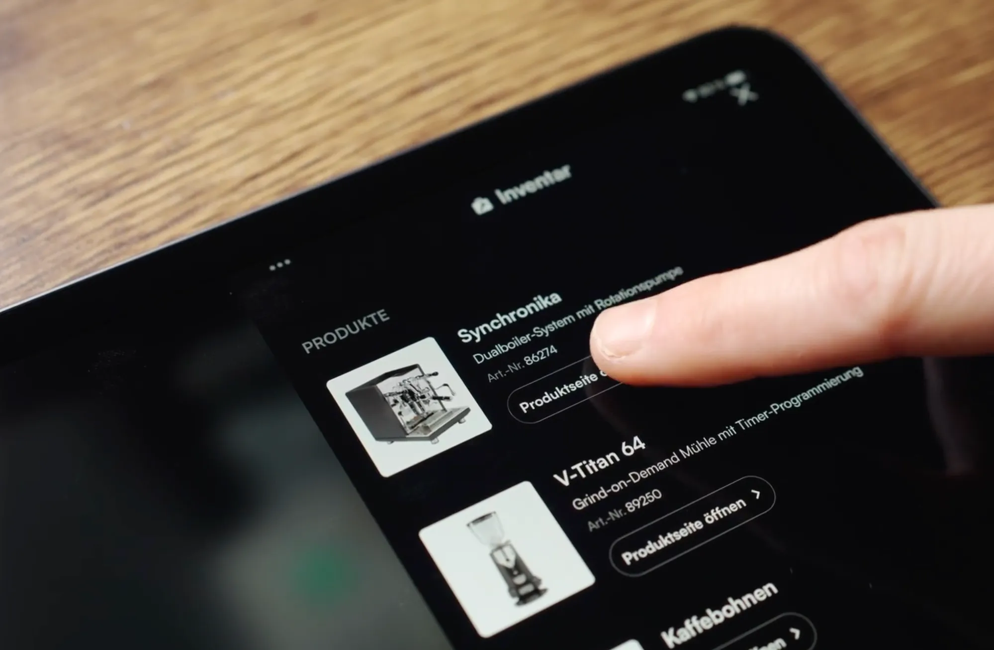 Tablet zeigt die Inventar-Funktion einer interaktiven Videoanleitung: ein Finger tippt bei der Espressomaschine Synchronika mit der Artikelnummer 86274 auf den Button Produktseite öffnen.